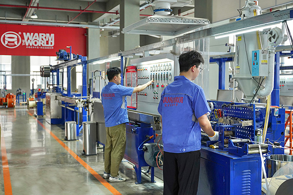 工人在操作電伴熱帶護套擠出設備 環(huán)瑞電熱供圖